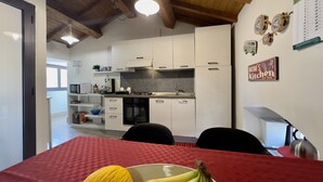 A modern kitchen with white cabinets, a red tablecloth, and a bowl of fruit. - Spacious apartment within walking distance of Duomo and Pescheria (Catania)