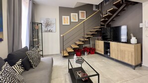 A modern living room with a sofa, coffee table, and a staircase leading to a bedroom. - Spacious apartment within walking distance of Duomo and Pescheria (Catania)