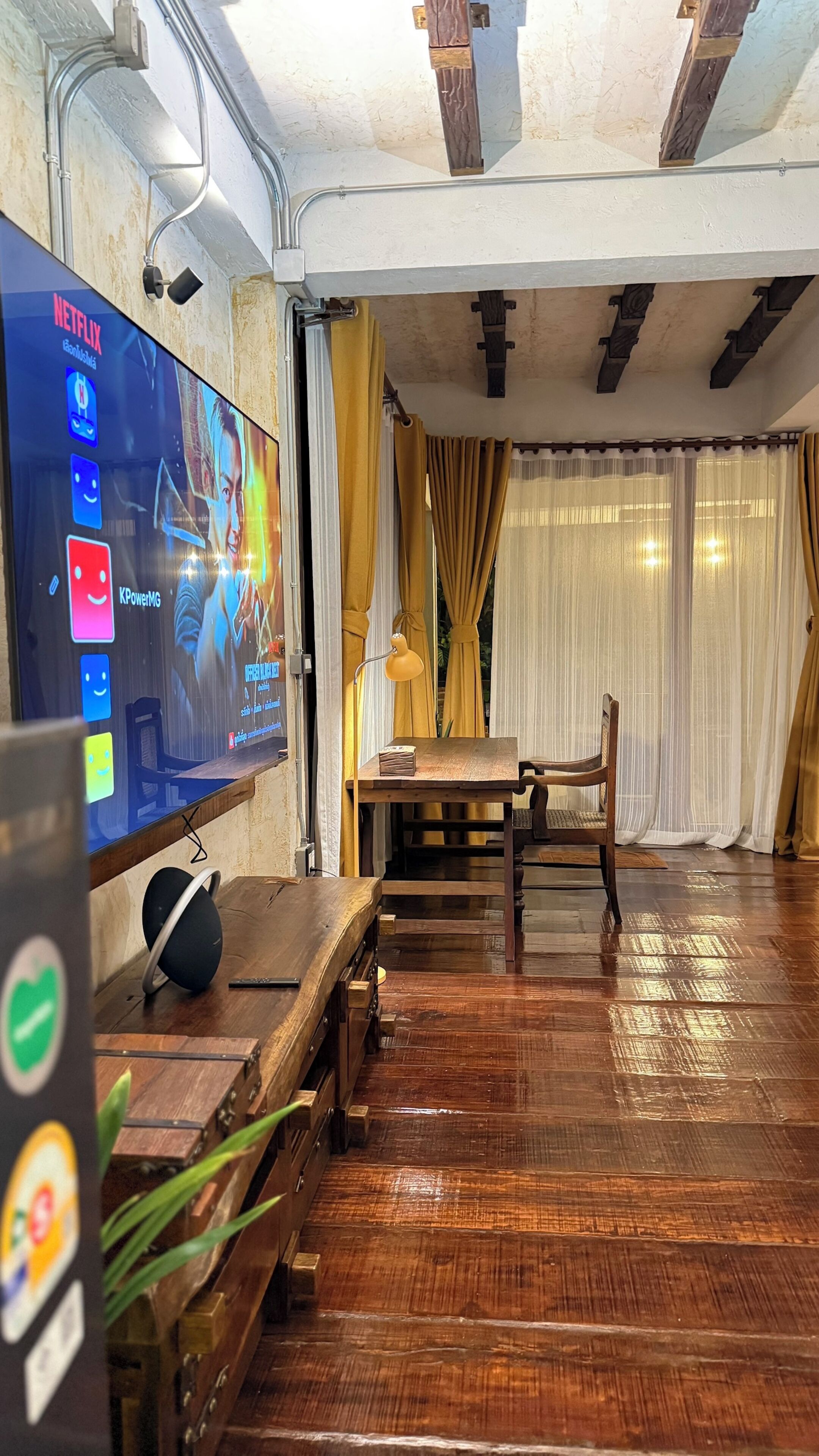 A living room with a flat-screen TV, wooden furniture, and a dining area.