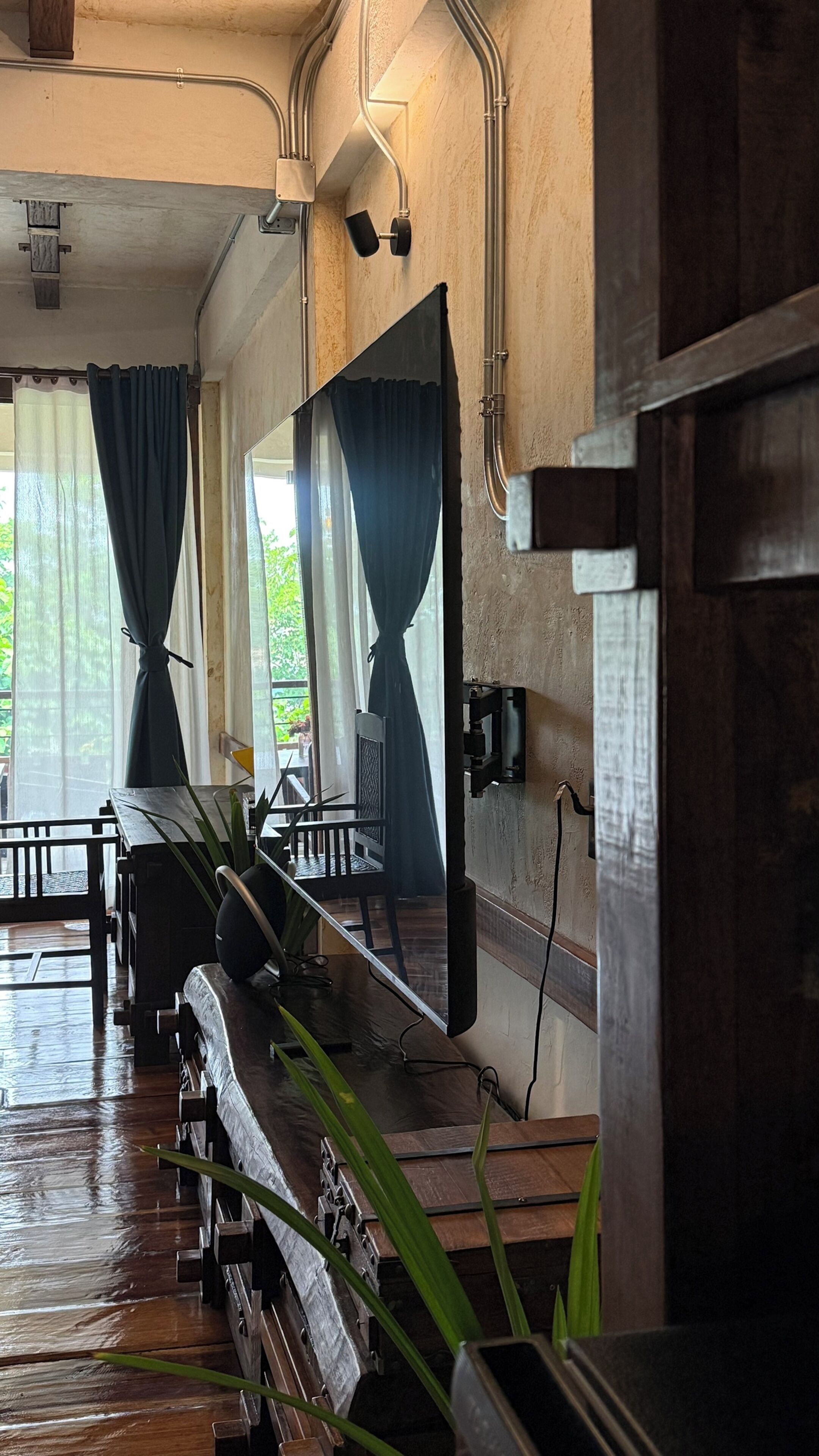 Una habitación con un banco de madera, un espejo grande y una ventana con cortinas.