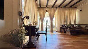A cozy room with wooden floors, a desk with a lamp, a chair, and a sofa with cushions.