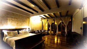 A spacious bedroom with a large bed, wooden flooring, and a ceiling with exposed beams.