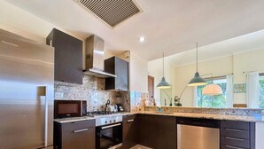 Une cuisine moderne dotée d’appareils électroménagers en acier inoxydable, de meubles de rangement aux couleurs sombres et d’un plan de travail en marbre.