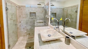 Une salle de bain moderne avec deux lavabos, une douche et un miroir.