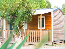 Una cabaña de madera con un porche, una ventana y una puerta.