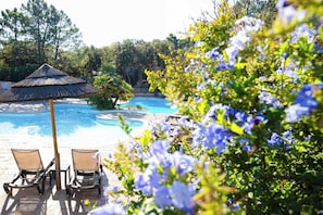 Una piscina al aire libre de temporada, sombrillas
