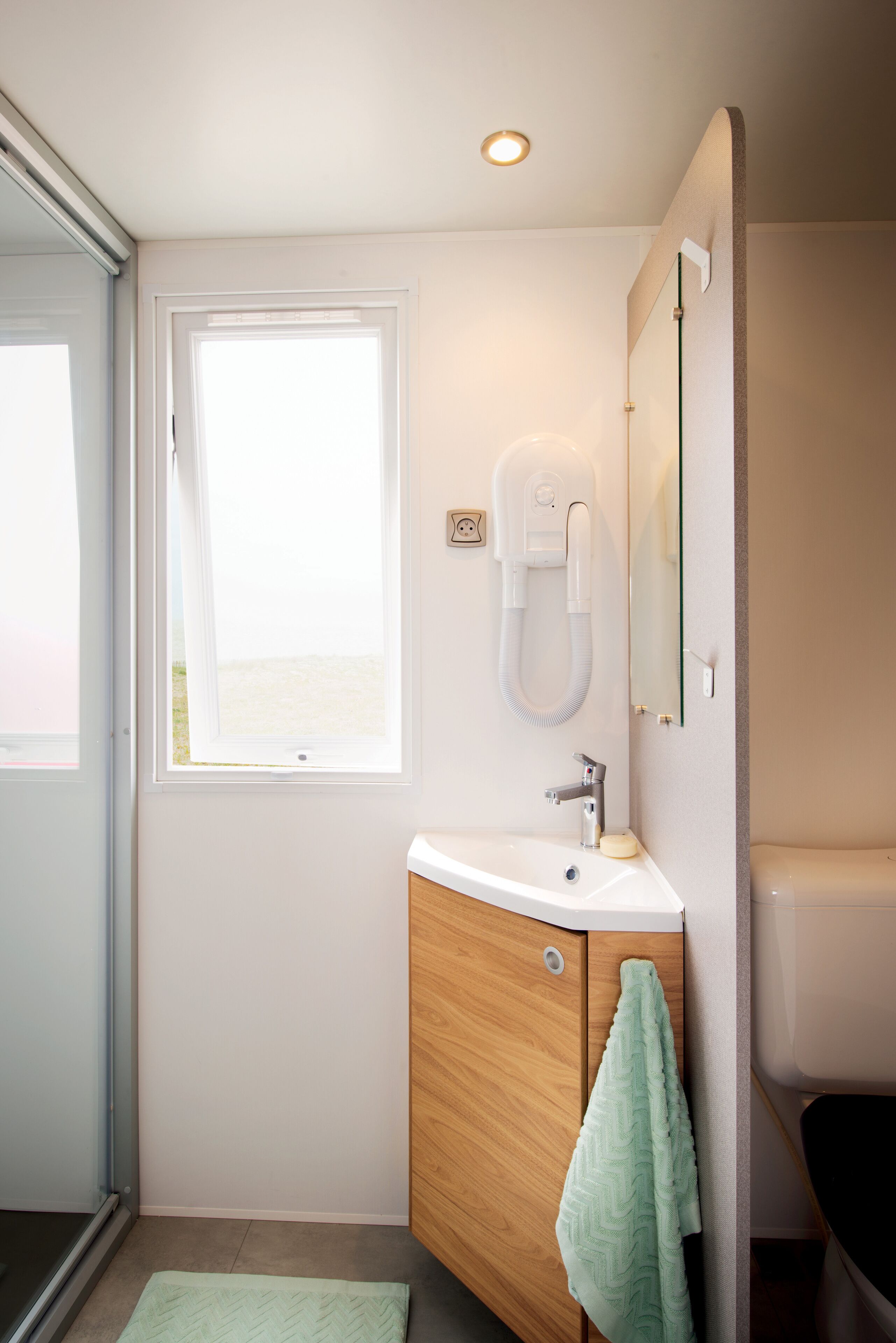 A bathroom with a window, a sink, a towel, and a mirror.