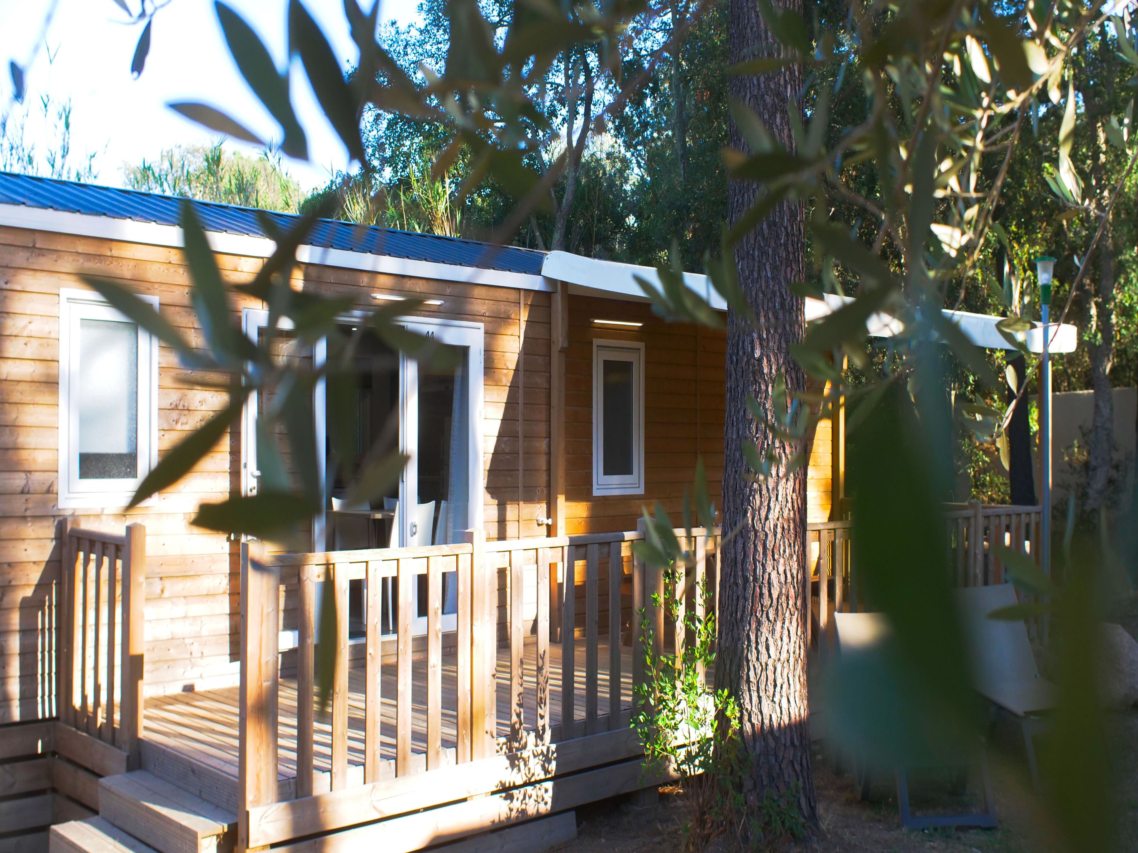 Una cabaña de madera con terraza, ventanas amplias y puerta.