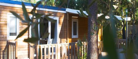 Una cabaña de madera con terraza, ventanas amplias y puerta.