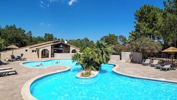 Relax by the resort pool surrounded by lush greenery and comfortable lounge chairs.