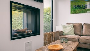 En moderne stue med et stort vindue, en brun lædersofa, et træbord og fletkurve.