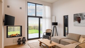 En moderne stue med en stor skydedør, et fladskærms-tv, en sofa, et sofabord og en gulvlampe.