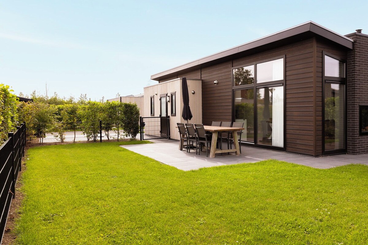 A modern two-story house with a patio, a dining area, and a large glass door.