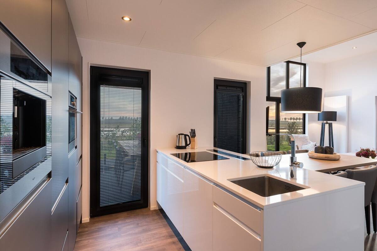 A modern kitchen with a central island, built-in appliances, and large windows offering a view of the countryside.