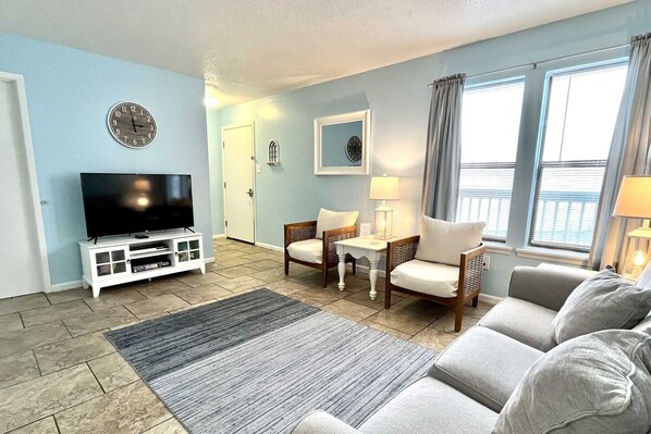 A living room with a flat-screen TV, two armchairs, a sofa, a coffee table, and a rug. - Ocean Reef 108 1 Bedroom Condo (Gulf Shores)