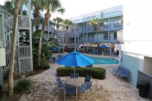 A courtyard with a pool, lounge chairs, and umbrellas. - Ocean Reef 108 1 Bedroom Condo (Gulf Shores)