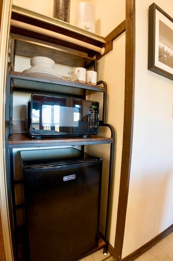 Una kitchenette compacta con microondas y refrigerador pequeño.