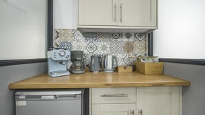 A compact kitchen with a dishwasher, a coffee maker, a kettle, and a wooden box on the counter. - Unique Exclusive Pub Sleeping up to 26 People (Pontardawe)