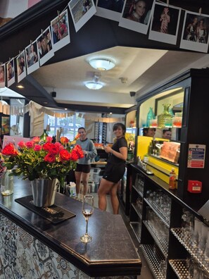 Una zona de bar con mostrador, un jarrón de flores y una copa de vino.