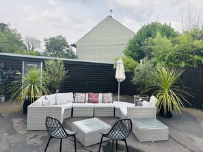 A modern outdoor seating area with a sectional sofa, two square tables, and black metal chairs. - Unique Exclusive Pub Sleeping up to 26 People (Pontardawe)