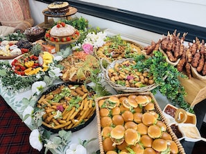 A buffet table with various food items including cakes, sandwiches, and snacks.