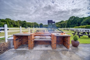 A barbecue area with brick grill stations, picnic tables, and a lifeguard tower. - Unique Exclusive Pub Sleeping up to 26 People (Pontardawe)