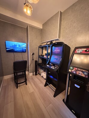 Una habitación con una consola de videojuegos, un televisor y una silla.