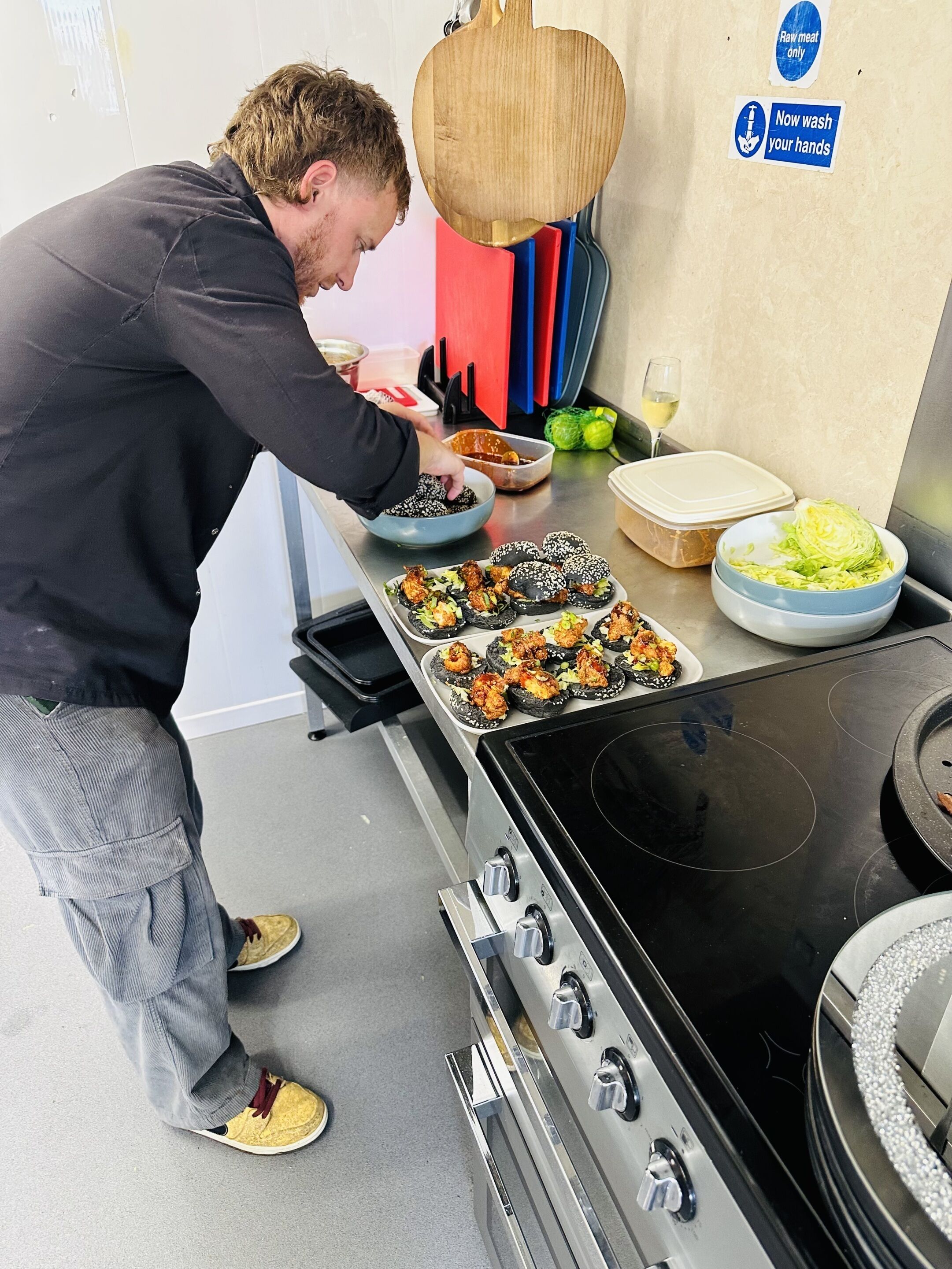 A person preparing food in a kitchen with a stove, a sink, and various cooking utensils.