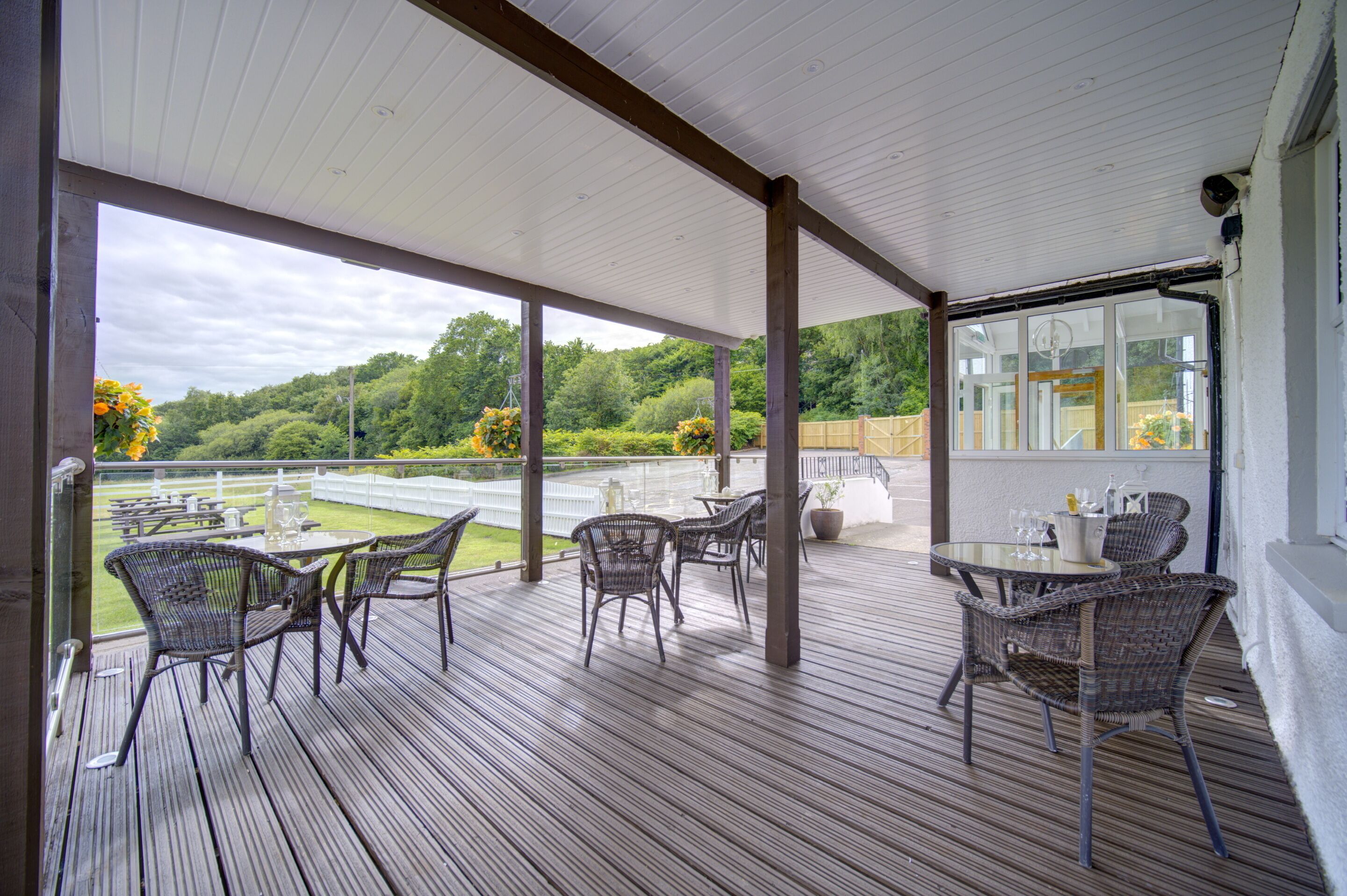 Un patio techado al aire libre con mobiliario de mimbre y vistas a un campo de golf.