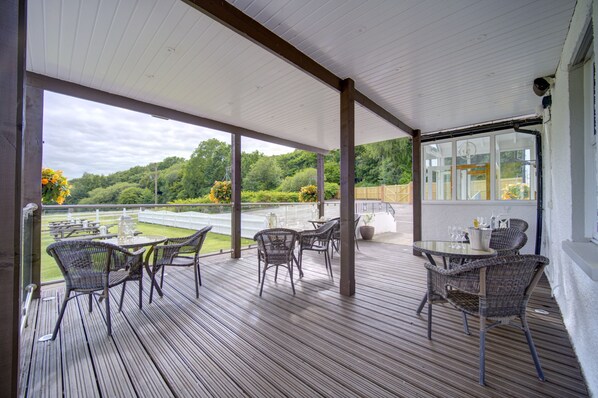 A covered outdoor patio with wicker furniture and a view of a golf course.