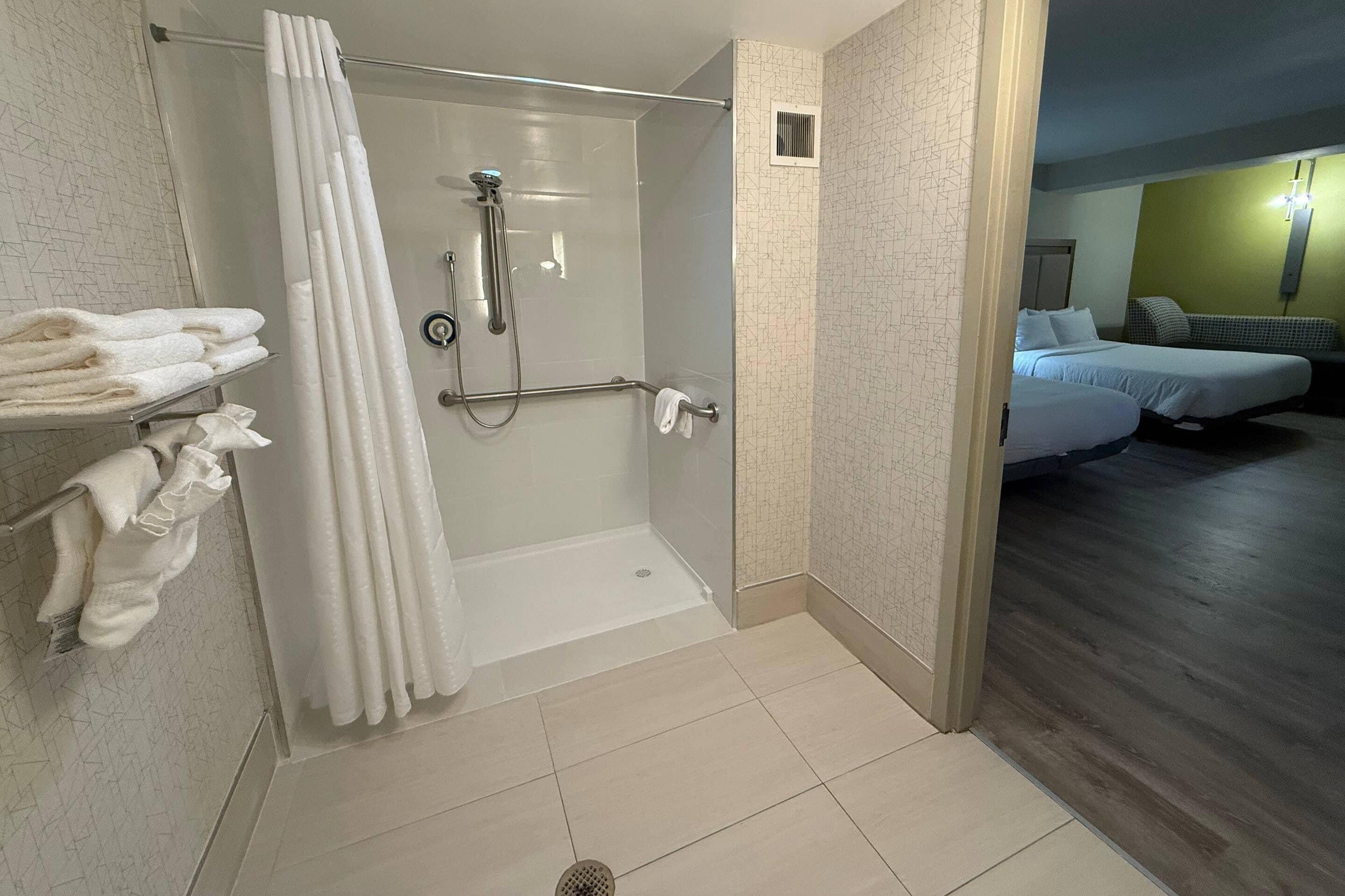 Une salle de bain moderne équipée d’une douche, d’un porte-serviettes et d’un rideau de douche visible.