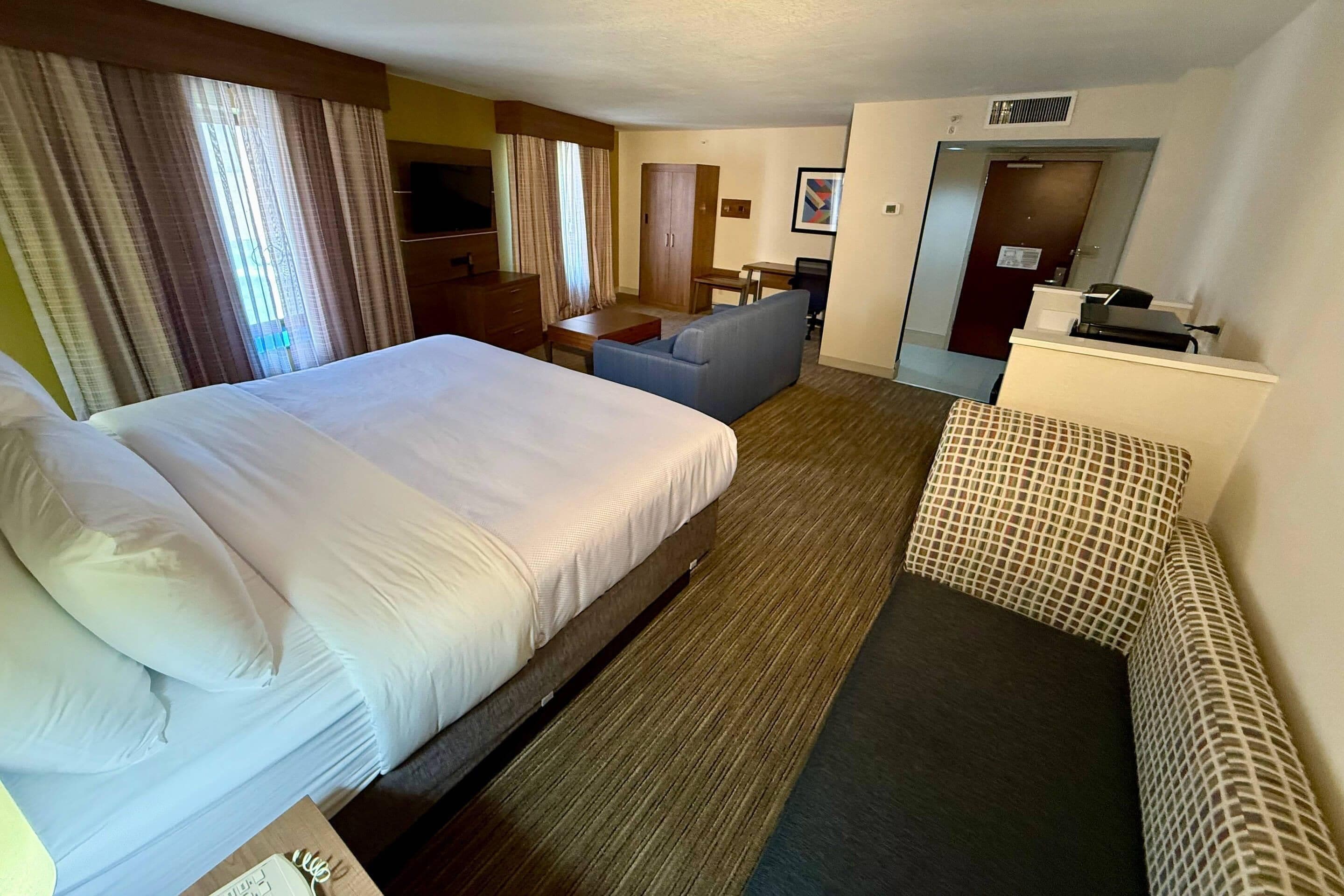 Ein Hotelzimmer mit einem großen Bett, einer Sitzecke, einem Schreibtisch und einem Fernseher.