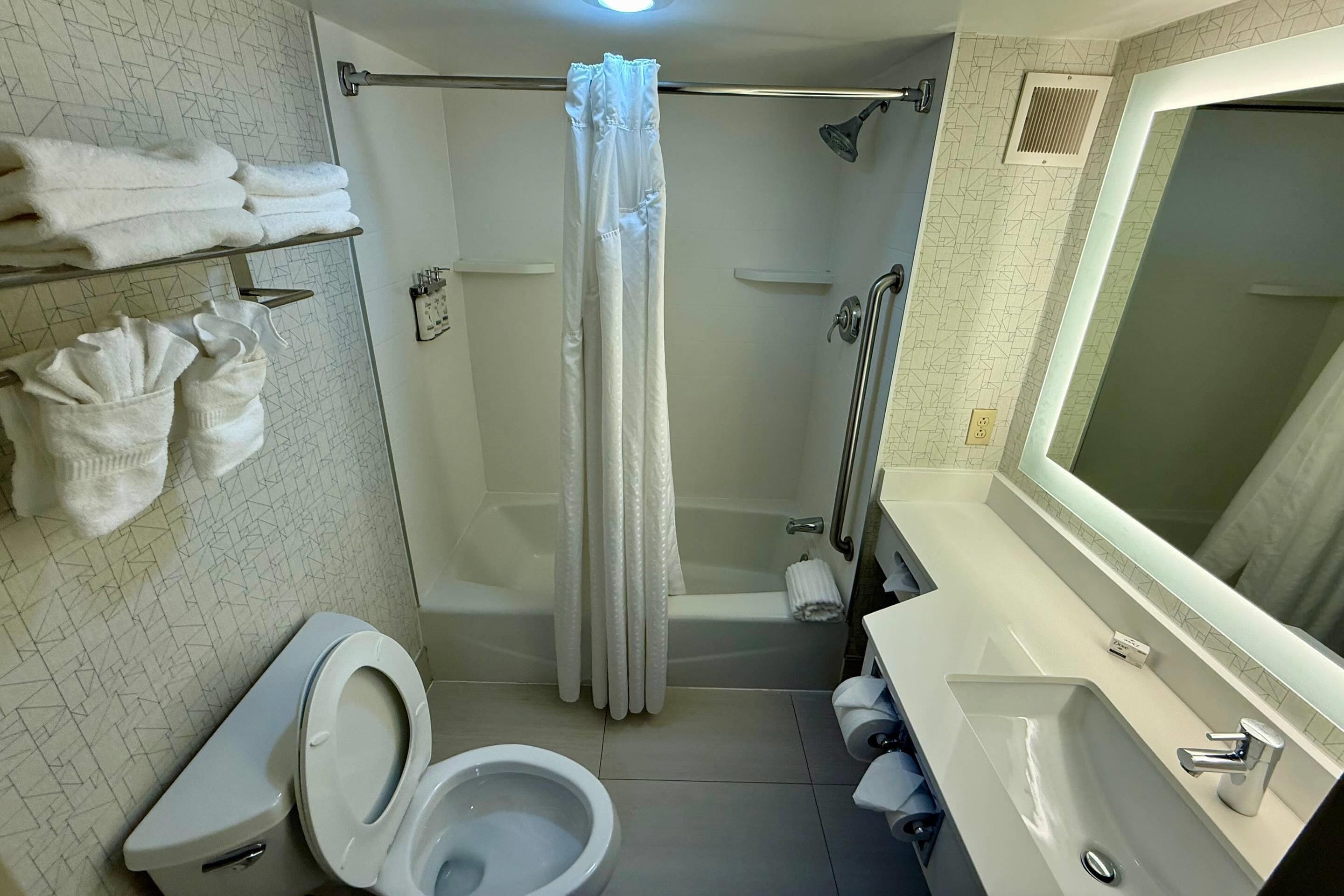 A bathroom with a toilet, shower, and sink.