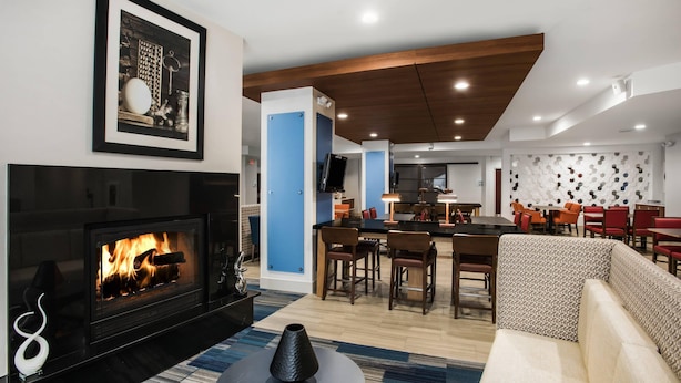 Una sala de estar moderna con chimenea, un comedor con sillas y una cocina al fondo.