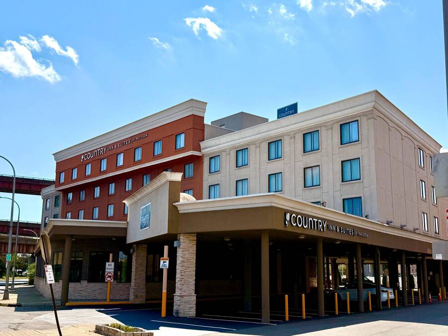 A hotel with a red and beige facade, multiple windows, and a sign indicating no parking for trucks.