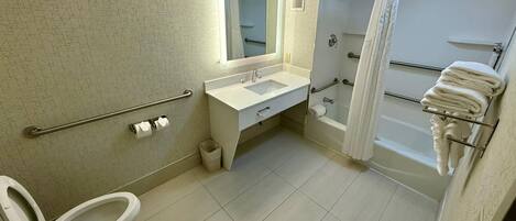 Une salle de bain équipée de toilettes, d’un lavabo, d’un miroir, d’une douche et d’un porte-serviettes.