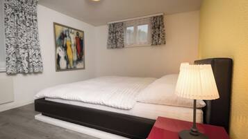 A bedroom with a bed, a red nightstand, a lamp, and a painting on the wall.
