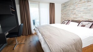 A bedroom with a large bed, a desk, and a view of a balcony. - Panoramarestaurant Hotel Roggerli  (Hergiswil)