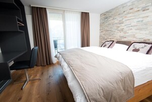 Un dormitorio con una cama grande, un escritorio y vistas a un balcón.