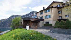 A restaurant with a wooden exterior, a view of a lake, and a mountainous backdrop. - Panoramarestaurant Hotel Roggerli  (Hergiswil)