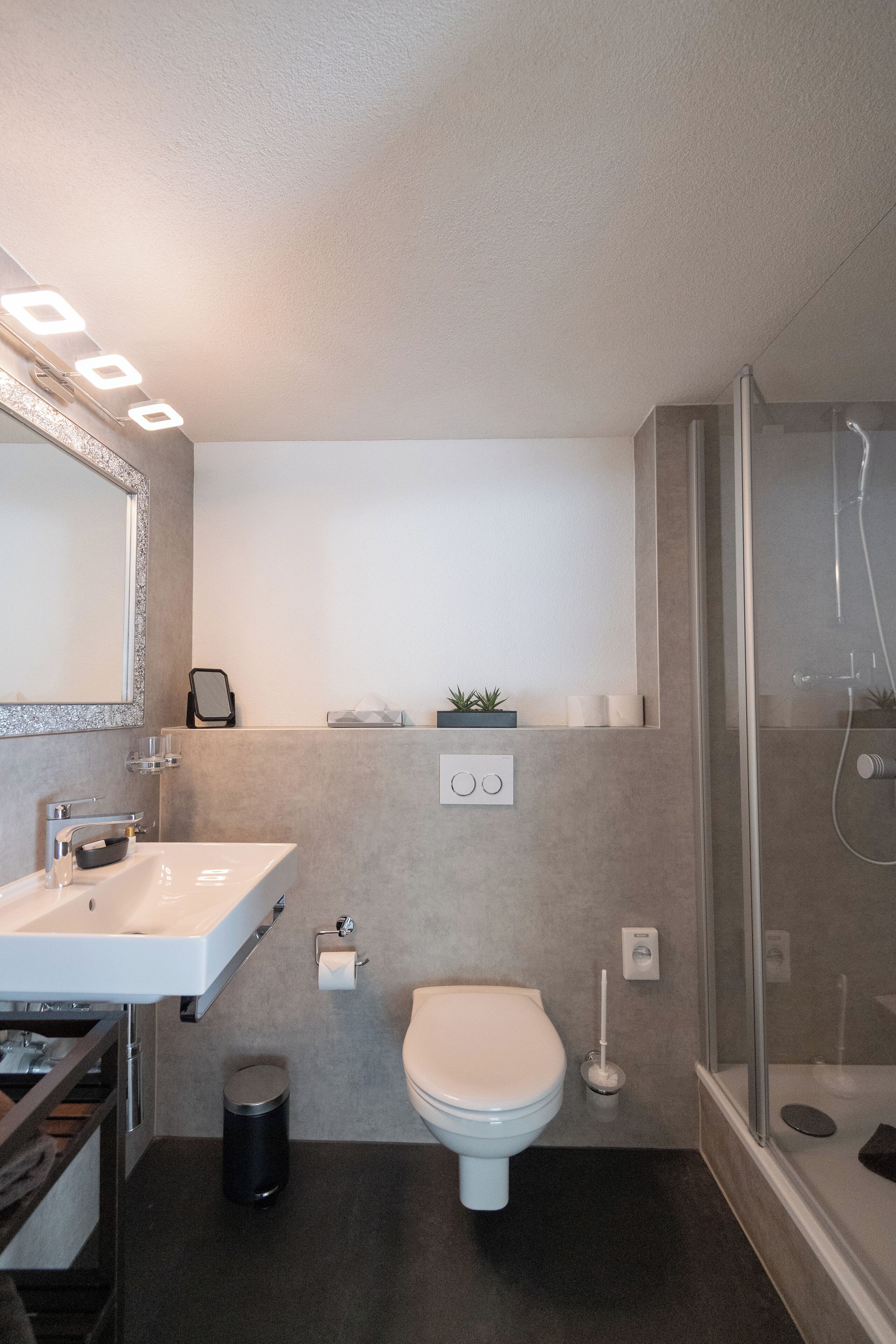 Un baño moderno con lavamanos, inodoro y ducha blancos.