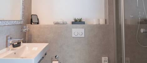 Un baño moderno con lavamanos, inodoro y ducha blancos.