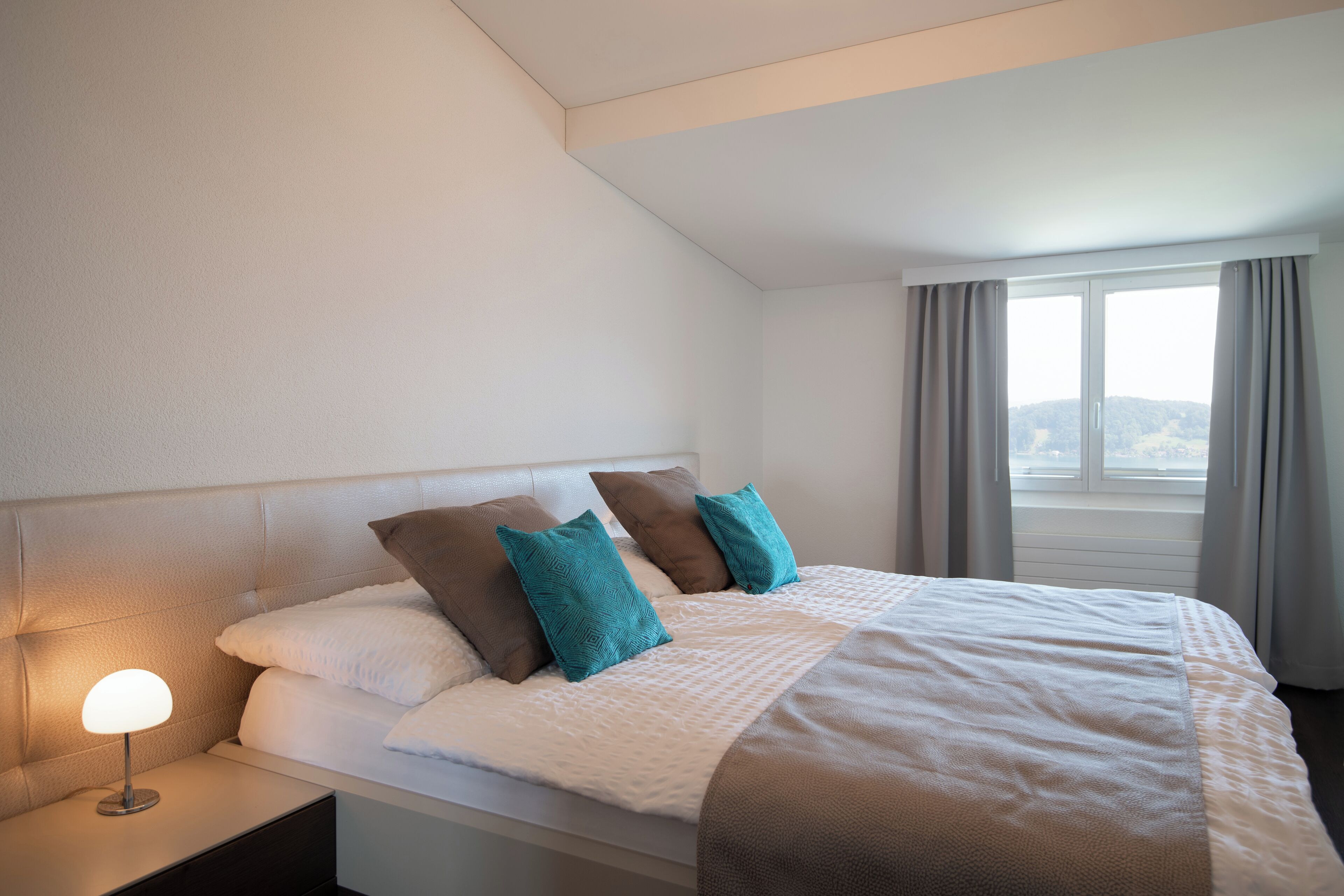 A hotel room with a bed, a nightstand, and a window with curtains.