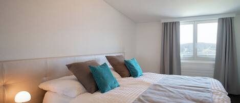 A hotel room with a bed, a nightstand, and a window with curtains.