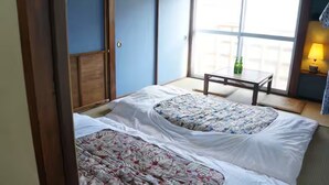 Una habitación con dos camas, una mesita y vistas al exterior a través de un ventanal amplio.
