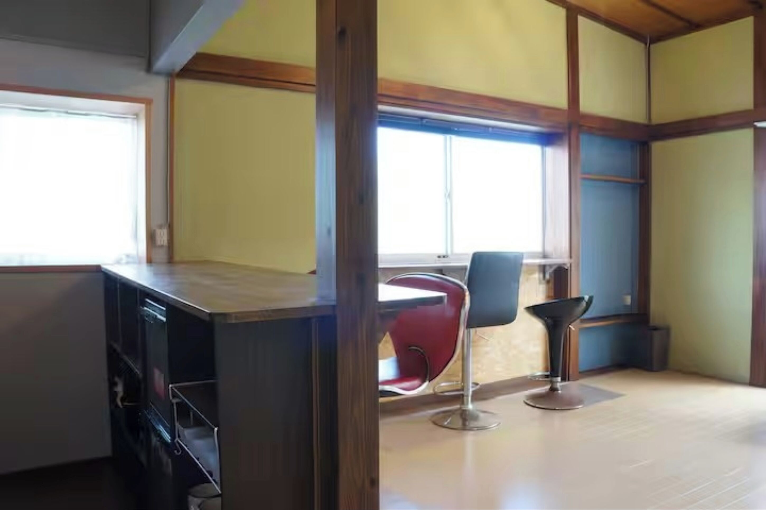 A room with a wooden floor, a desk with a chair, and a window.