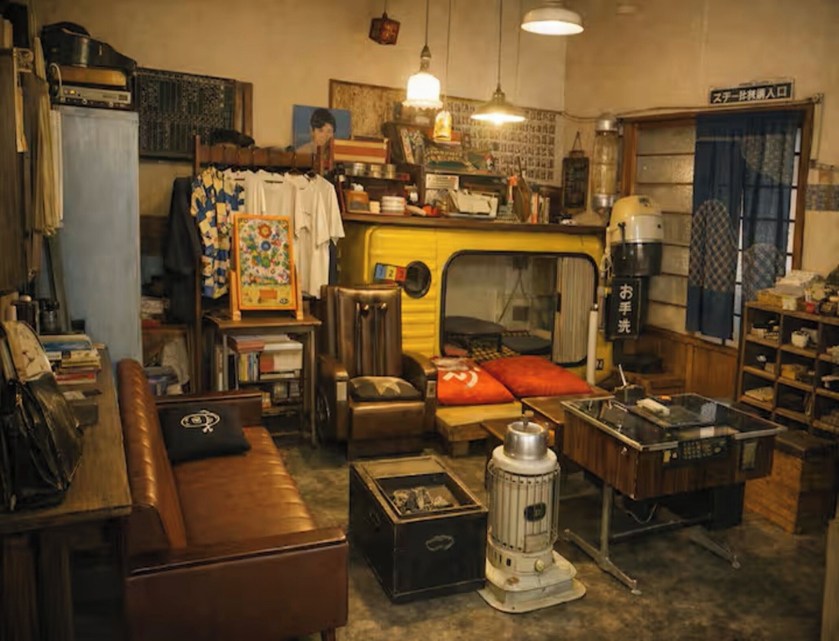 Een gezellig, compact leefruimte met een kitchenette, een bank, een klein tafeltje en een retro fornuis.