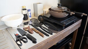 Una encimera de cocina con estufa, ollas, sartenes y varios utensilios.
