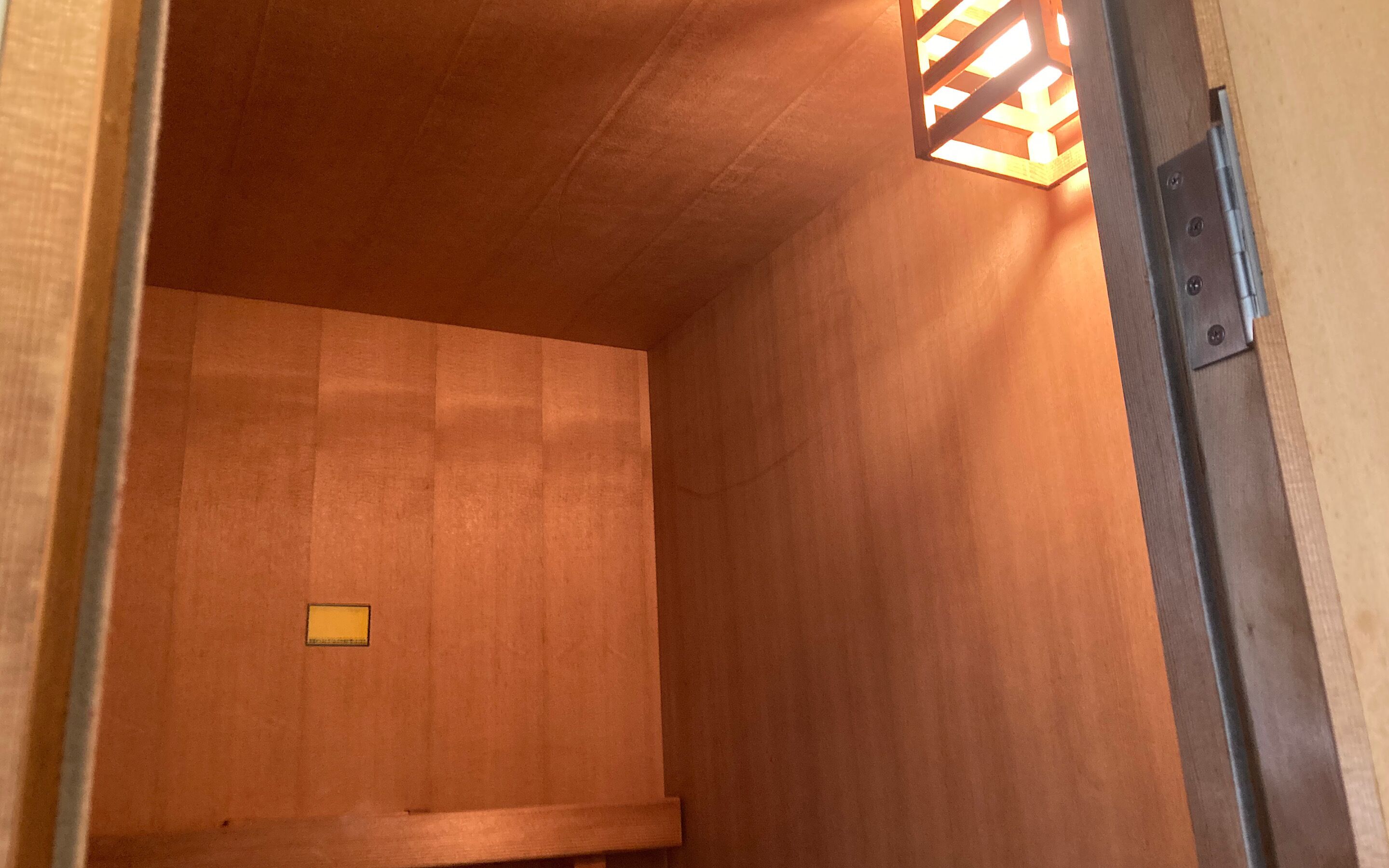 Un interior de madera con un banco y una pequeña señal amarilla.