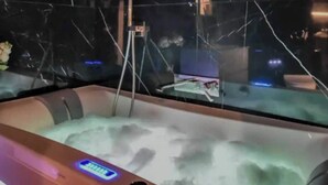 A hot tub with a digital control panel, a glass partition, and a visible water pump.